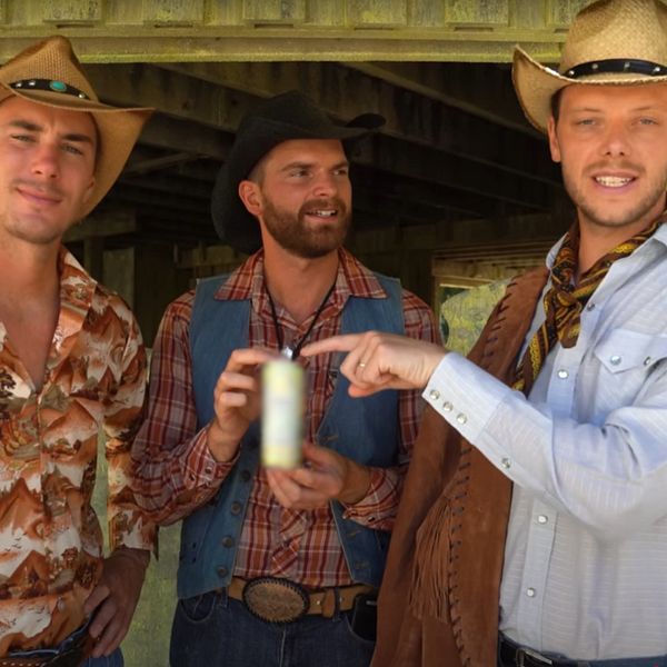 Tre personer i cowboykläder står tillsammans utanför en träbyggnad.