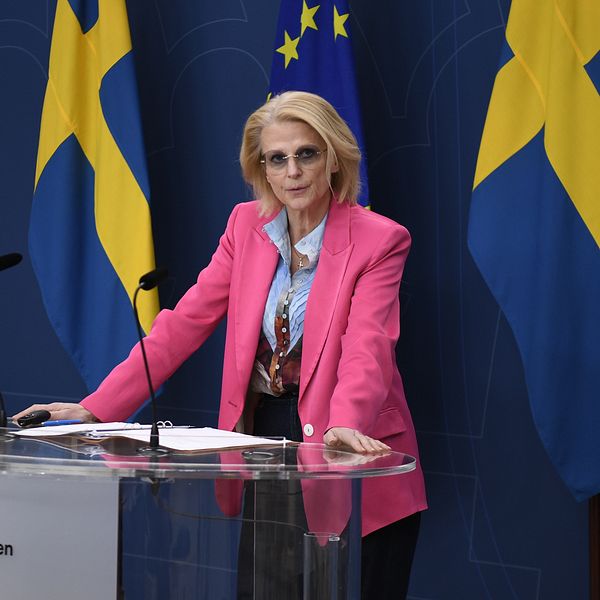 Elisabeth Svantesson (M) vid podium framför svenska och EU flaggor.