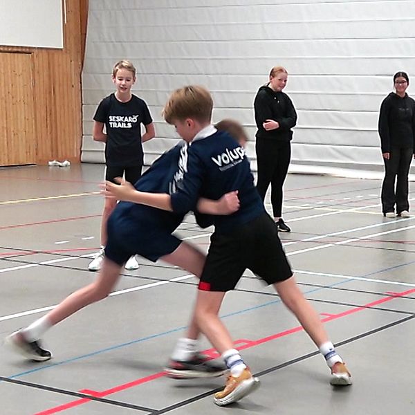 Två skolelever i Luleå tränar ”kamplek” medan lärare och elever tittar på.