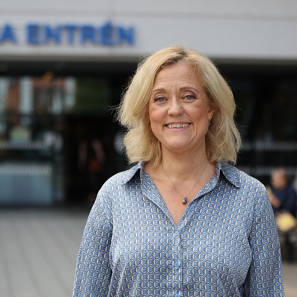 Kvinna i blå skjorta med mönster står framför universitetssjukhuset i LInköping
