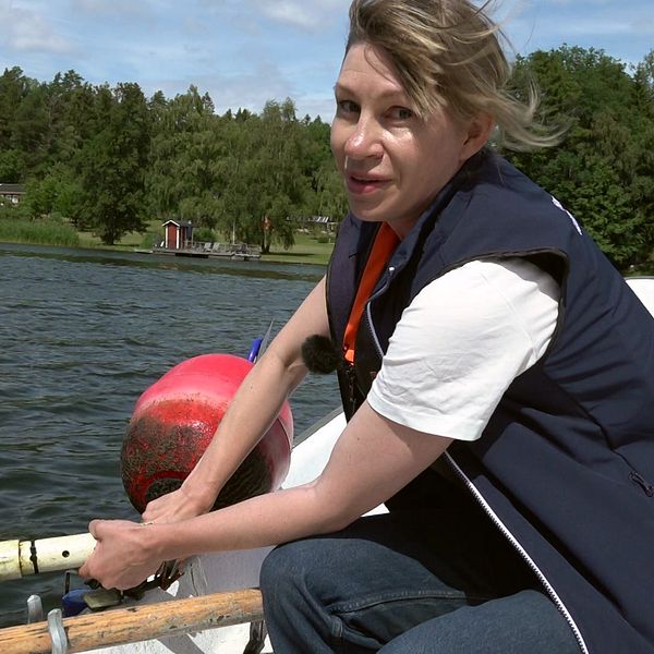Kvinna i båt med mätinstrument.
