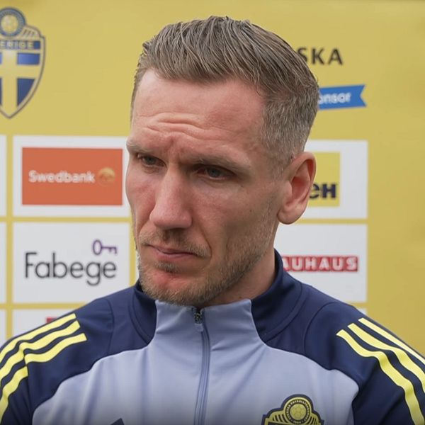 Person i Sveriges fotbollslandslags träningsoverall vid en presskonferens.
