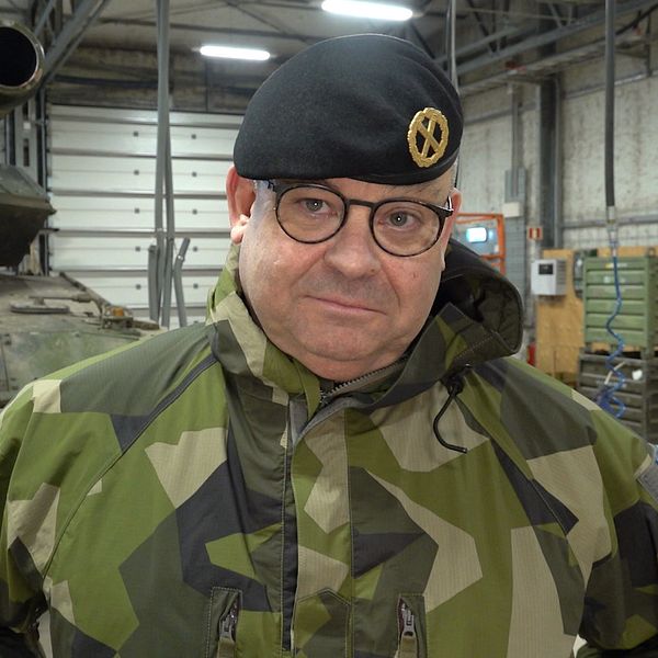 Michael Claesson i militäruniform står framför en stridsvagn inomhus.