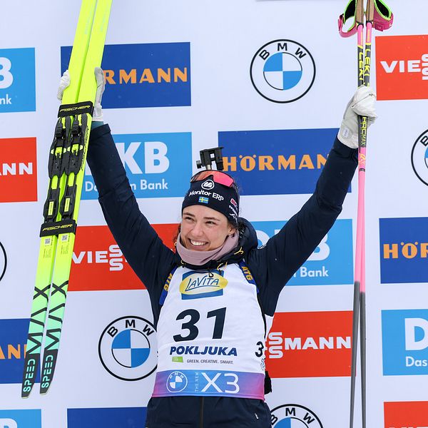 Skidskytten Hanna Öberg sträcker upp armarna i en segergest under prisutdelningen.