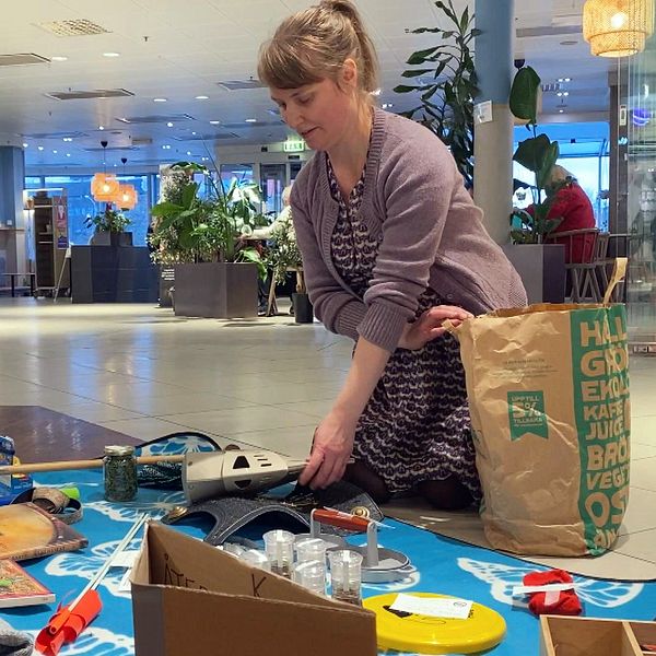 En kvinna lägger ut leksaker på en matta i ett köpcentrum.