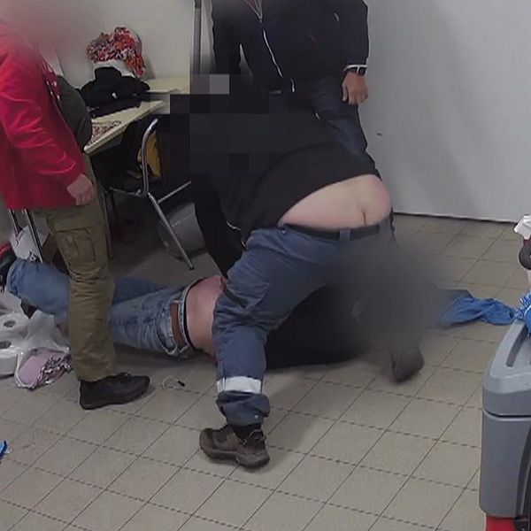 Väktaren i Luleå sätter sig på den misstänkte glasstjuvens rygg medan två andra män står bredvid.