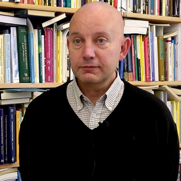 Nationalekonomen Jesper Stage står framför en bokhylla.