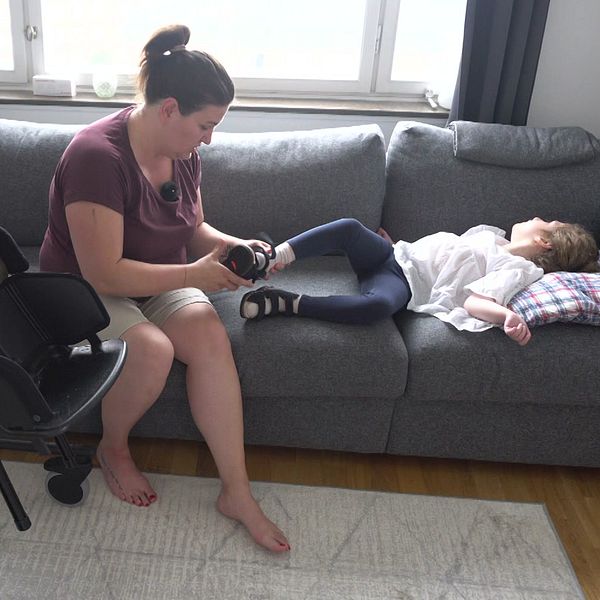 Mamma hjälper dotter som ligger i soffan på med sko