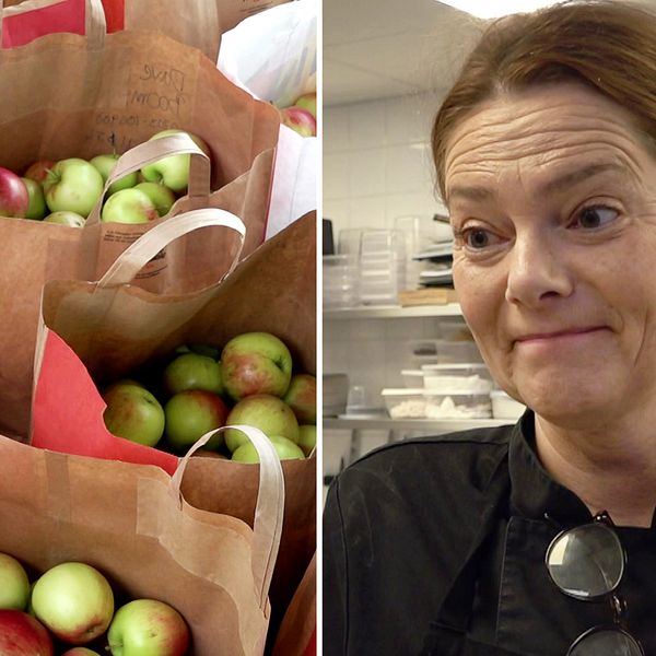 Flera papperspåsar fyllda med äpplen bredvid popologen Bibbi Kringlund i en köksmiljö på Kulinarika i Västra Ämtervik utanför Sunne, klädd i en svart kockrock med köksutrustning synlig i bakgrunden.