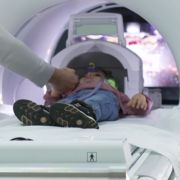 Ett barn åker in i en magnetröntgen-apparat.