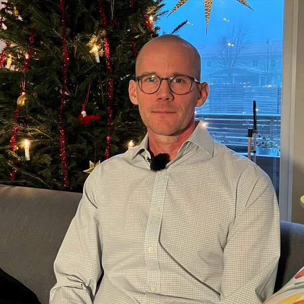 Man i glasögon framför julgran