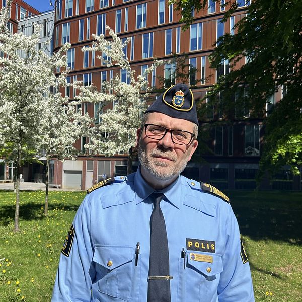 Robert Karlsson, biträdande regionpolischef framför två träd med vita blommor.