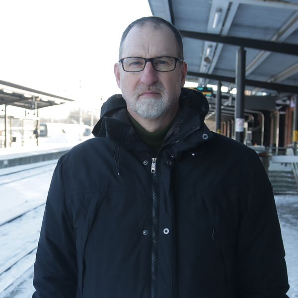 Man i svart vinterjacka och svarta glasögon står på perrongen vid Linköpings resecentrum.