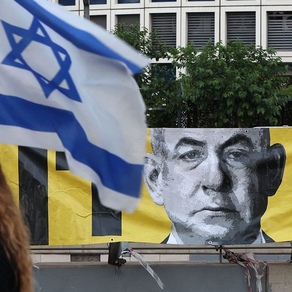 Person håller en israelisk flagga framför en avbildning av den israeliska premiärministern Benjamin Netanyahu.