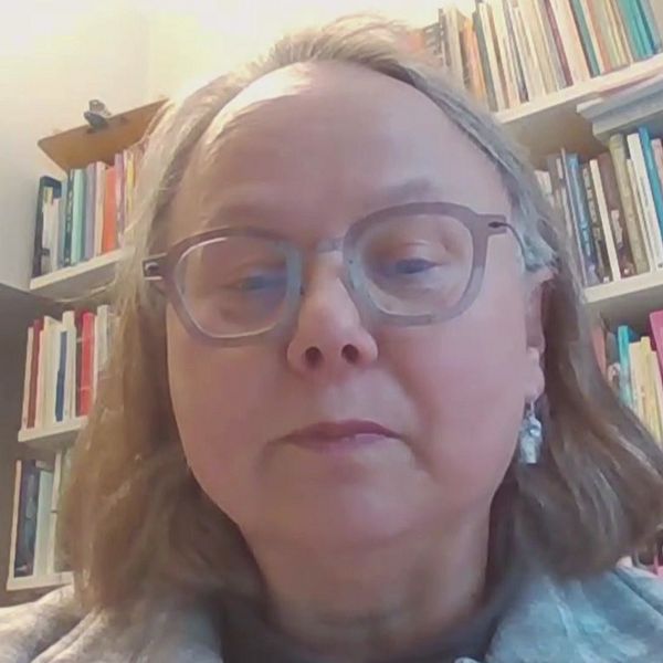 Kajsa Ahlstrand, professor i missionsvetenskap, sitter framför en bokhylla.