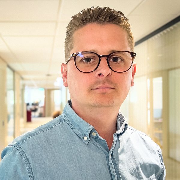 Alex Nejdemo i ljusblå skjorta i en kontorskorridor