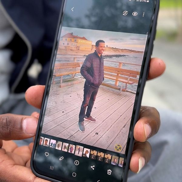 Man håller upp mobiltelefon och visar ett fotografi.