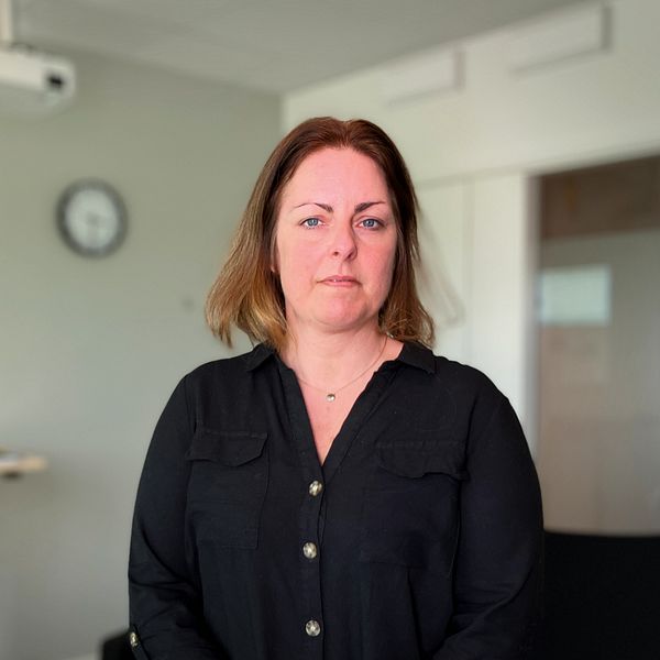 Liselott Åsberg, verksamhetschef på Centrum mot våld står i en svart skjorta i ett mötesrum i deras lokaler i Östersund.