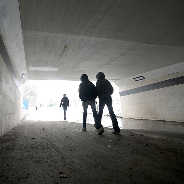 Tre personer går i en tunnel mot starkt ljus framöver.