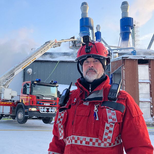 Räddningsledaren i röd jacka står framför branden i Hammerdal