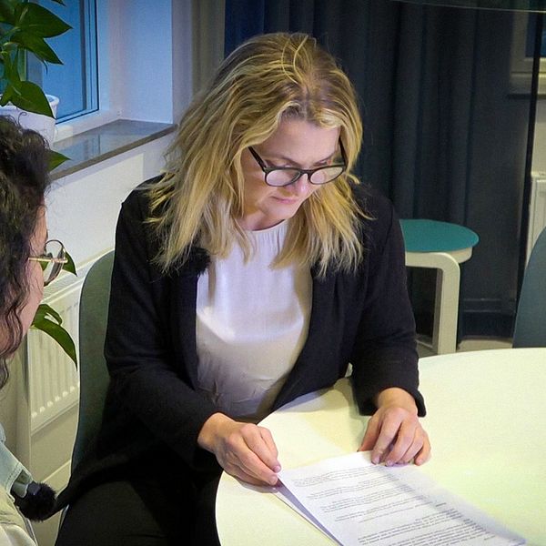 Helga Valdimarsdottir, distriktchef Väster på Poseidon, tittar på papper vid ett bord tillsammans med SVT:s reporter.