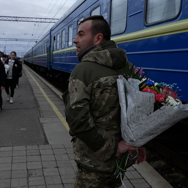 En soldat håller en blombukett bakom ryggen.