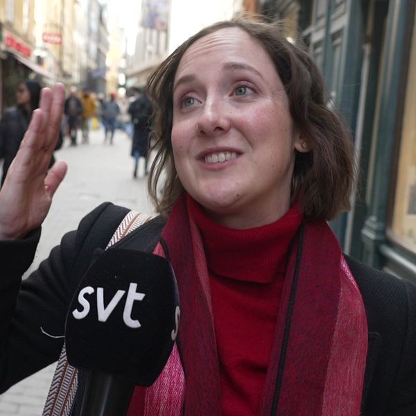 Person intervjuas av SVT på en gågata med butiker och förbipasserande i bakgrunden.