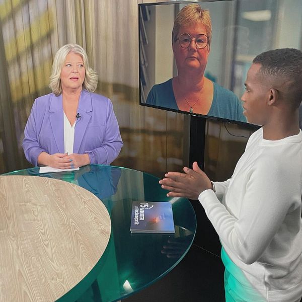 Socialtjänstministern Camilla Waltersson Grönvall (M) i samtal med programledaren Abdi Mohamed. En teckenspråkstolk står bredvid ministern.