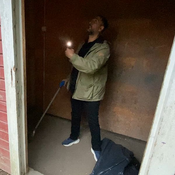 Oscar Tunedal, fritidspedagog på Blåsboskolan i Västerås lyser med en ficklampa i en av skolgårdens byggnader.