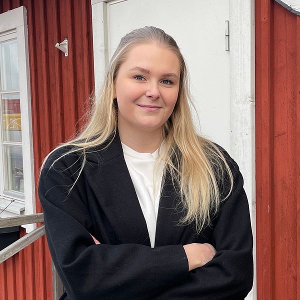 Jasmine Nilsson äger restaurangen Fiskerian i Hörvik. På bilden står hon utomhus med armarna i kors, hon står framför ett rött hus och tittar in i kameran.