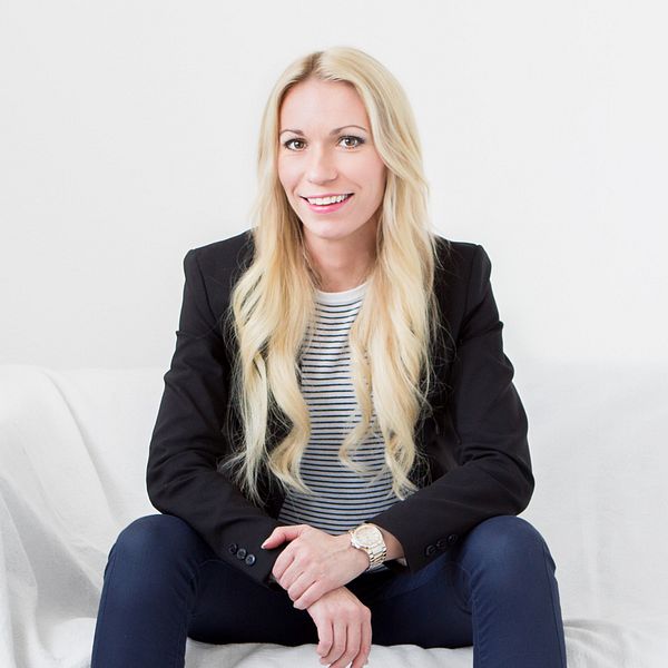 Jacqueline Joo sitter i en vit soffa, med en vitt vägg bakom sig.