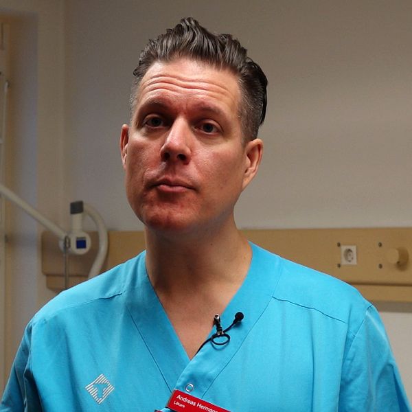 Sjukvårdspersonal i blå uniform står i ett rum med medicinsk utrustning.