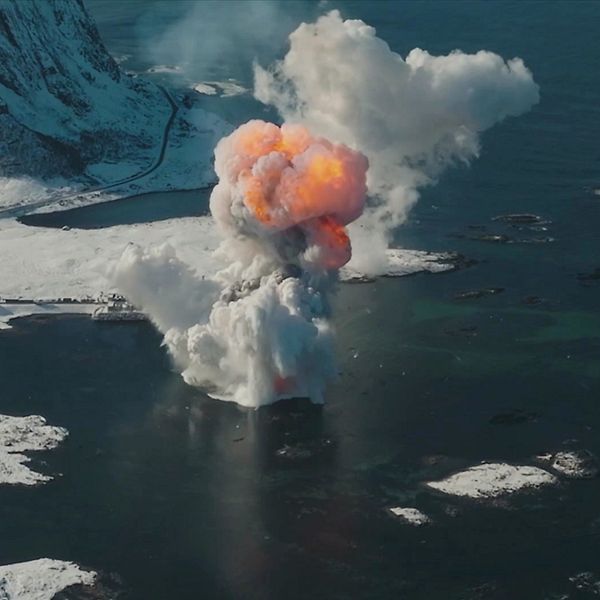 Raketen har precis träffat vattenytan och exploderat där en stor rökpelare med eld inuti stiger mot himlen.