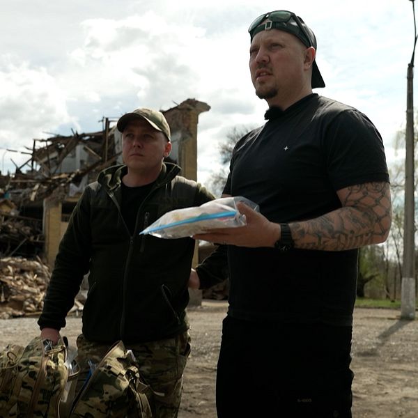 Två män står framför en söderbombad byggnad.