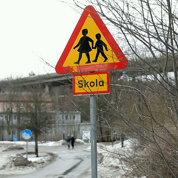 Bild på trafikskylt utanför skolbyggnad.