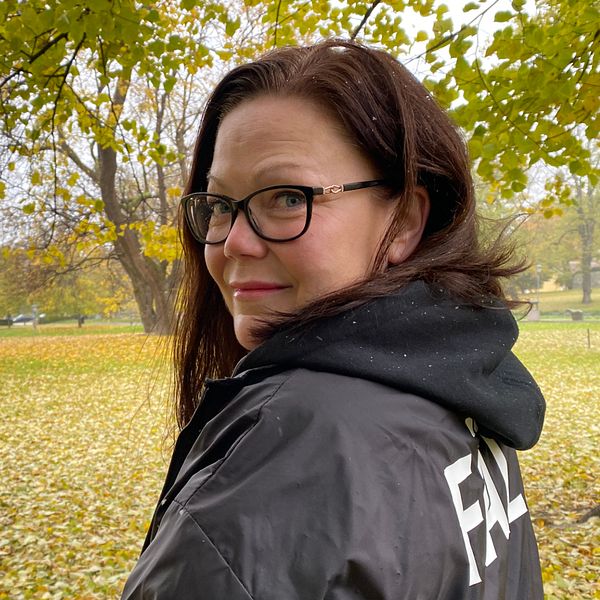 Kvinna med jacka med texten ”Fält” i Vasaparken i Västerås på hösten