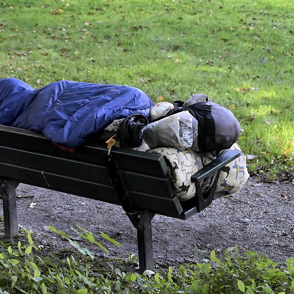 En person som sover ute på en parkbänk