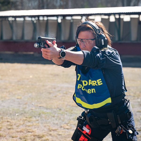 Kvinna på skjutbana siktar med pistol.