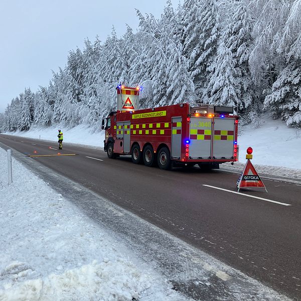 En räddningstjänstbil som står på E18, vid sidan av vägen syns snöiga träd