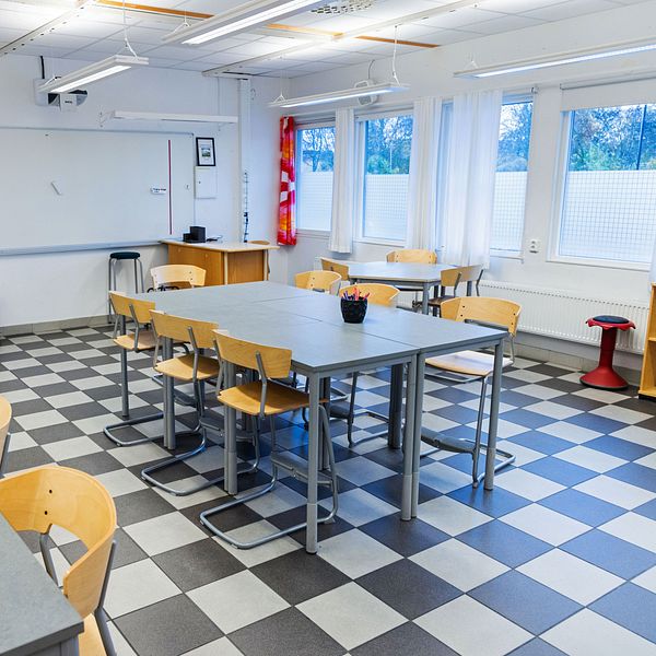 Ett klassrum med bänkar och stolar.