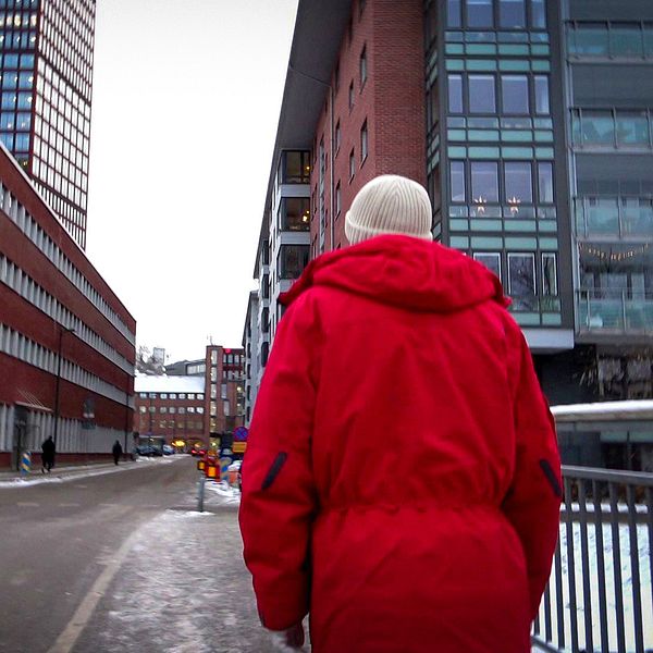 Man som går på gatan i Göteborg med röd vinter jacka.