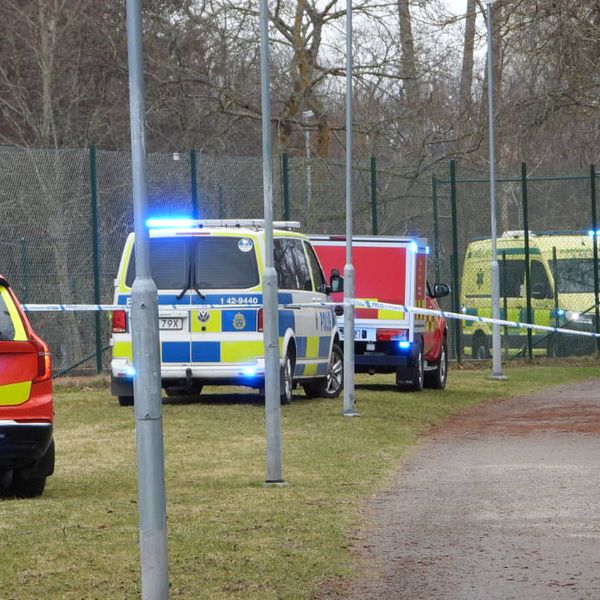 Ambulans och polisfordon med blåljus vid avspärrat område.