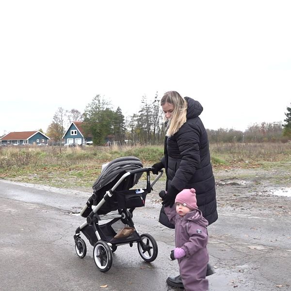 En mamma med barnvagn och barn.