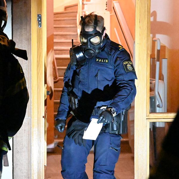 Polis med skyddsmask arbetar vid trapphus efter utsläpp av okänd vätska.