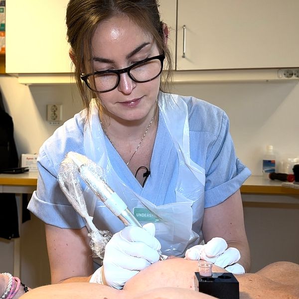 Undersköterskan Viktoria Philman sticker en tatueringspenna mot ett kvinnobröst.
