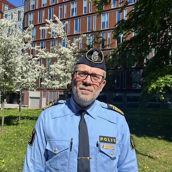 Robert Karlsson, biträdande regionpolischef framför två träd med vita blommor.