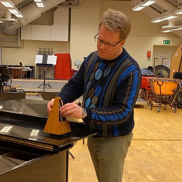 Man sätter igång en metronom som står på en flygel