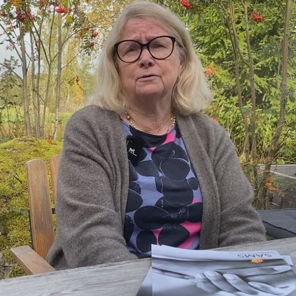 Anna-Lena Söderlund Törnell sitter vid ett bord utomhus med en rapport framför sig