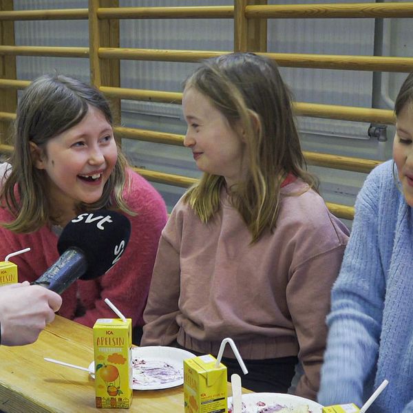 Till höger tre elever på en skola i Örebro som skrattar. Till vänster en cyklist som cyklar på vintern sedd bakifrån.