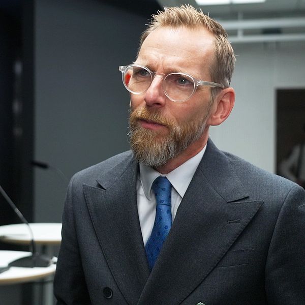 Socialminister Jakob Forssmed svarar på frågor om psykisk ohälsa på en pressträff. Han bär en grå kavaj med blå slips.